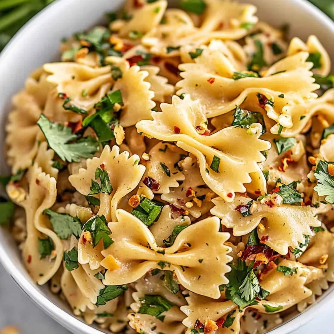 A bowl of pasta with green herbs.