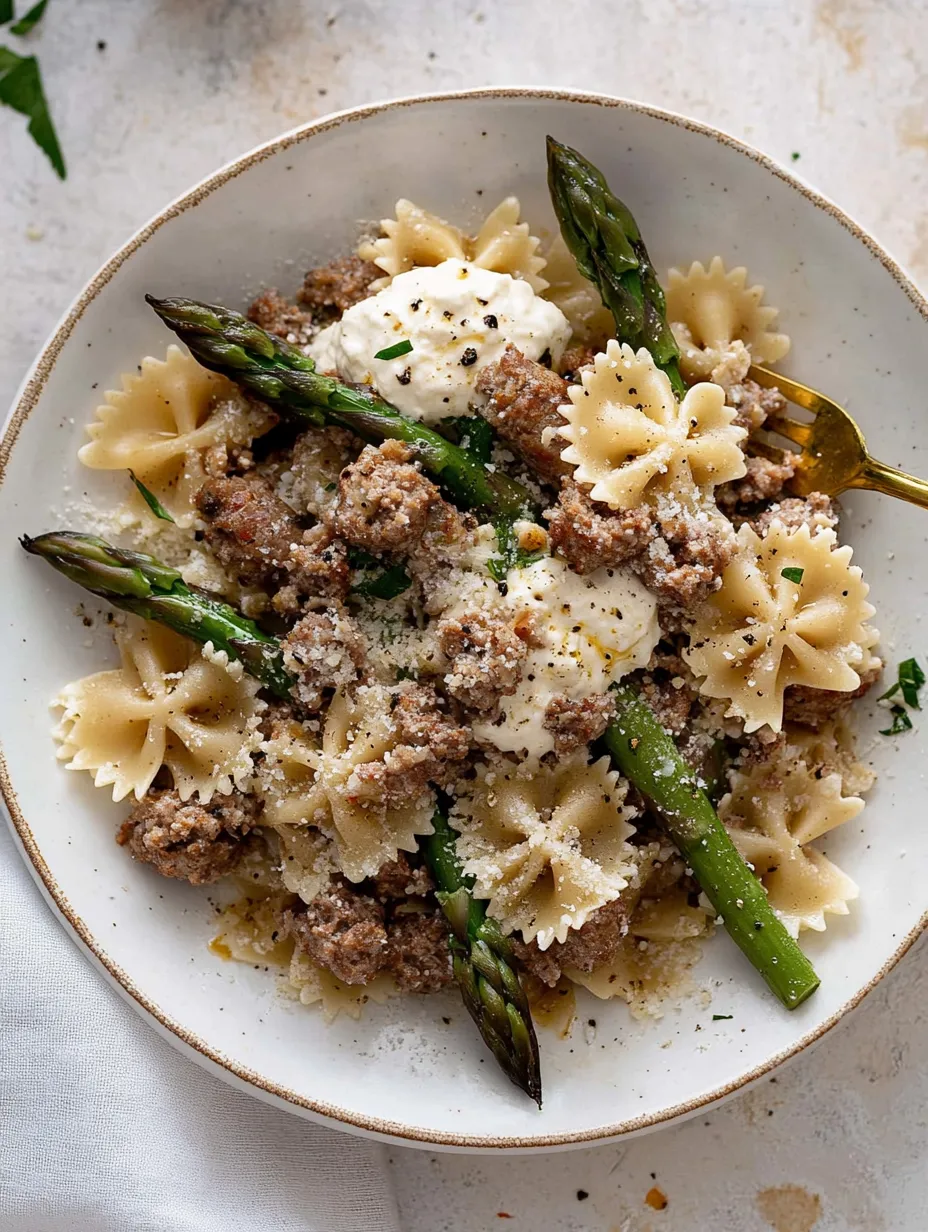 A bowl of pasta with meat and asparagus.