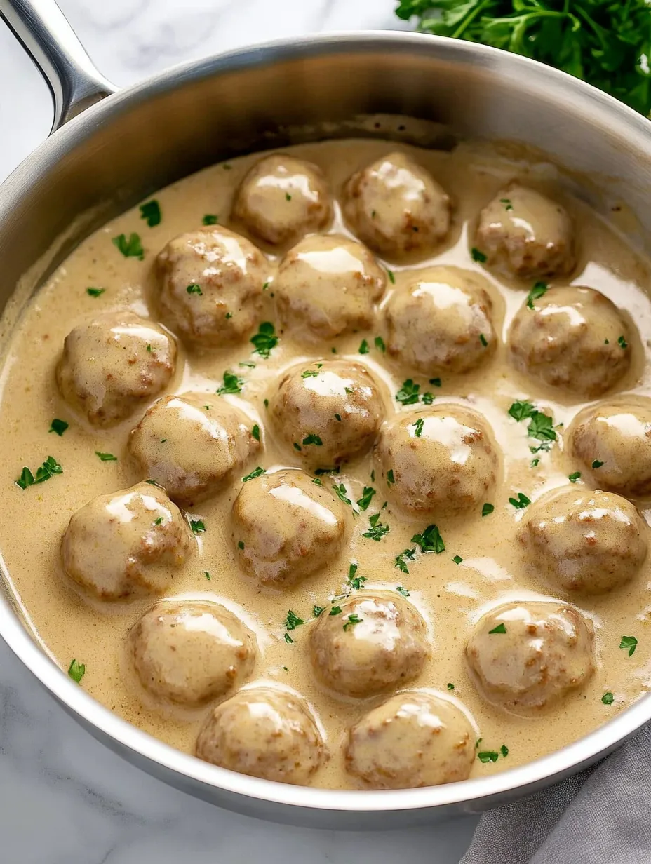 A pot of food with meatballs and a green herb.