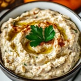 A creamy dip garnished with parsley in a bowl.