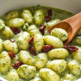 A bowl of pasta with red peppers and green sauce.