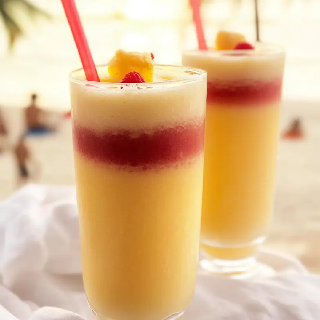 Two orange drinks in glasses with straws.