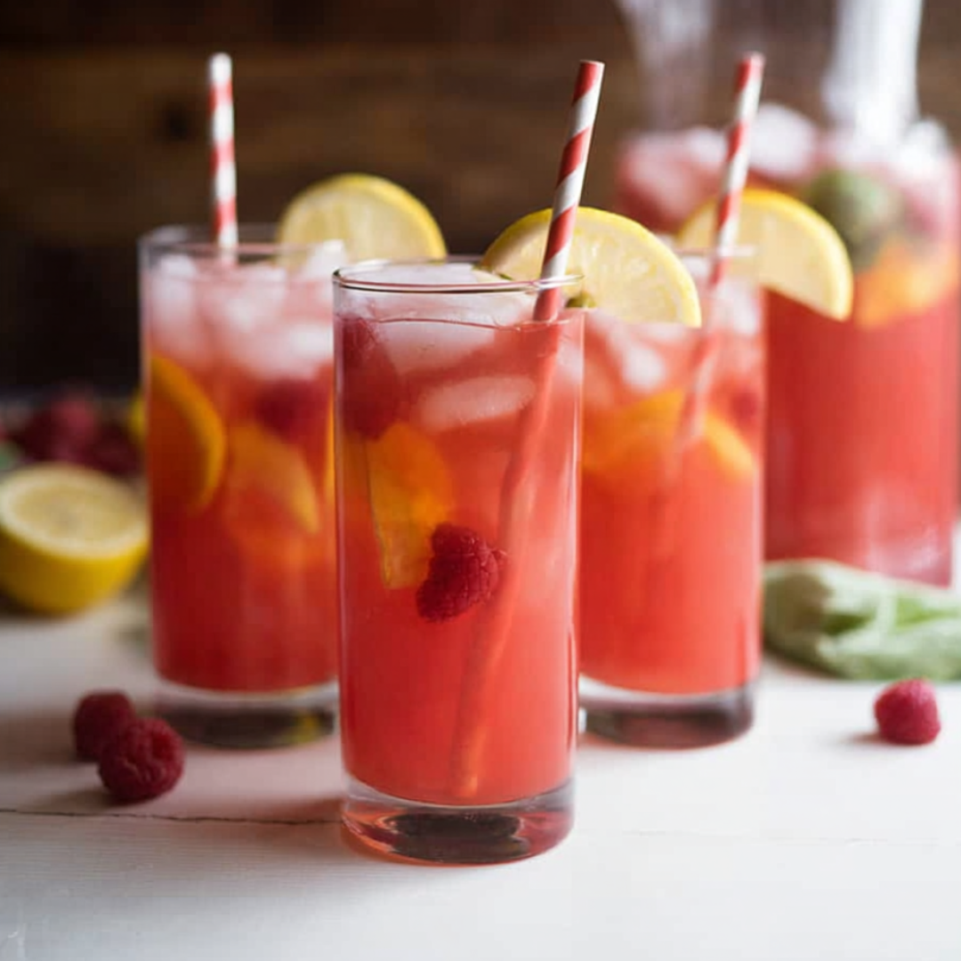 Three glasses filled with bright pink lemonade and striped straws.