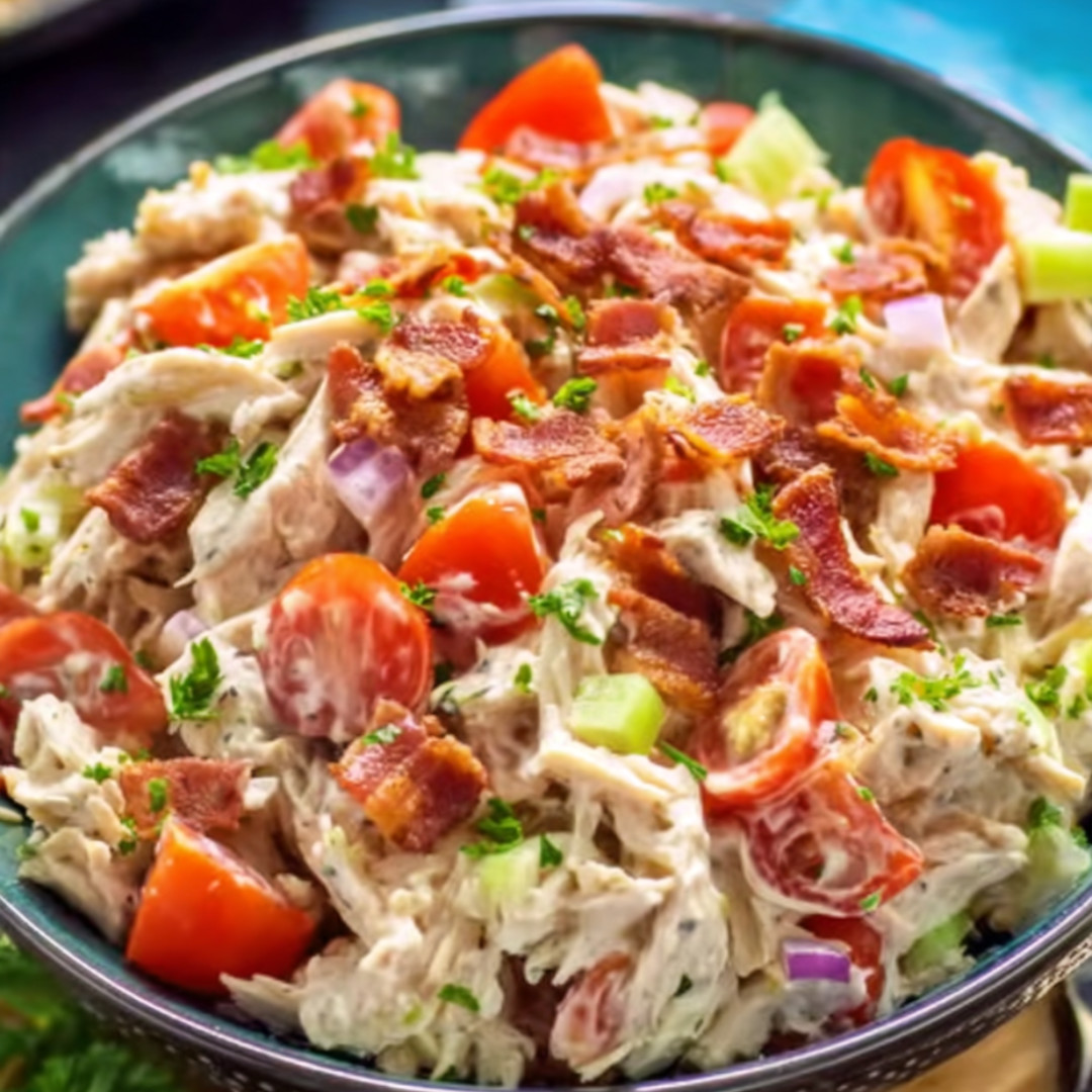 A bowl of chicken salad with tomatoes.