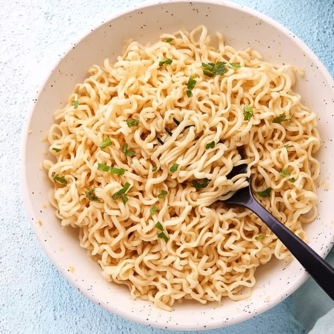 A bowl of noodles with green onions.