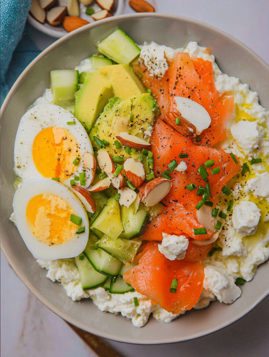 A plate of food with eggs, cucumbers, avocado, and smoked salmon.