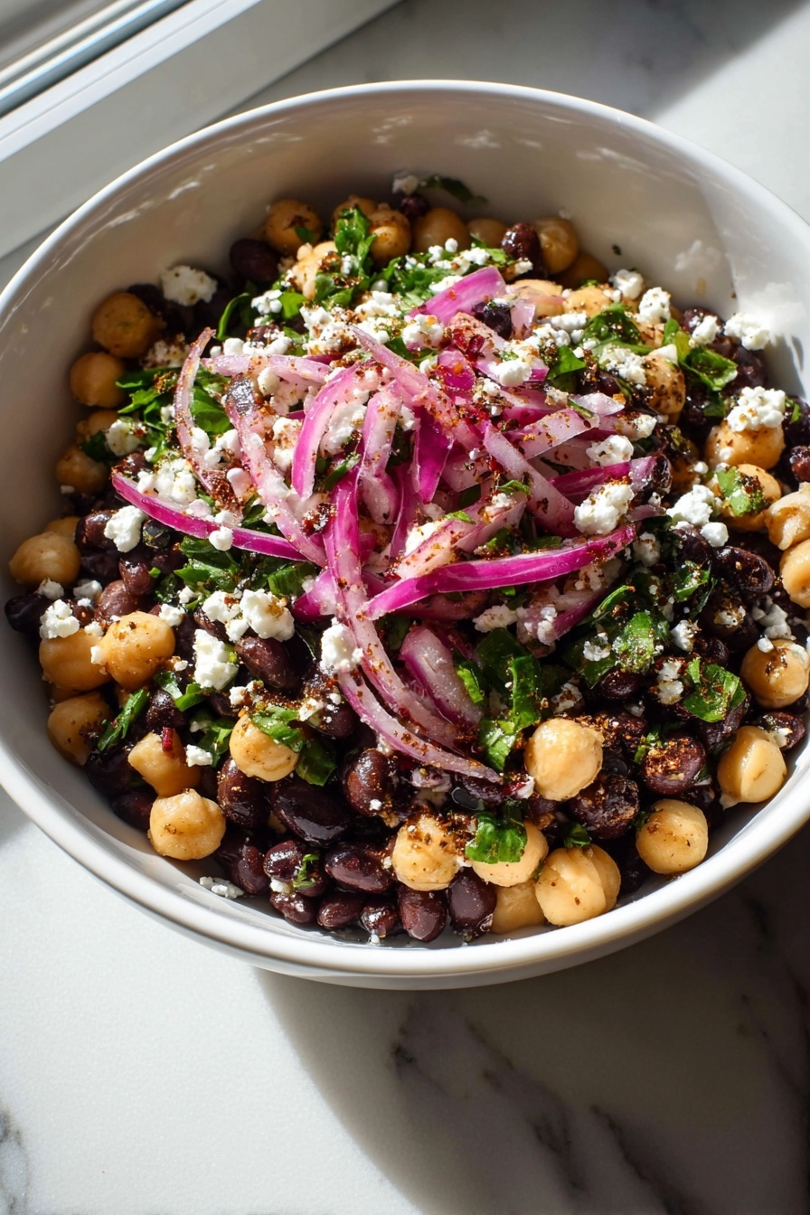 A bowl of salad with onions, olives, and feta cheese.
