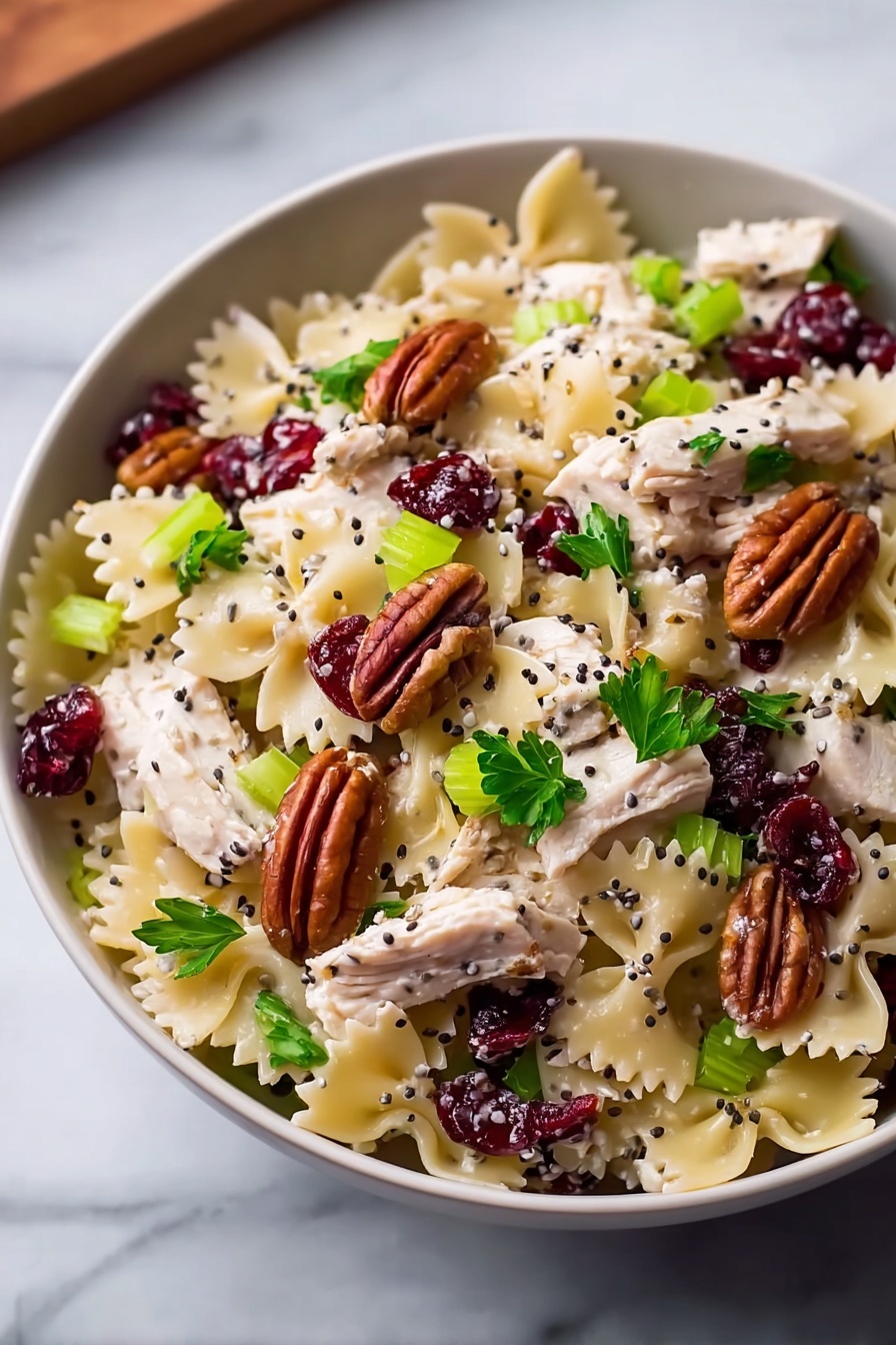 A bowl of pasta salad with cranberries and nuts.