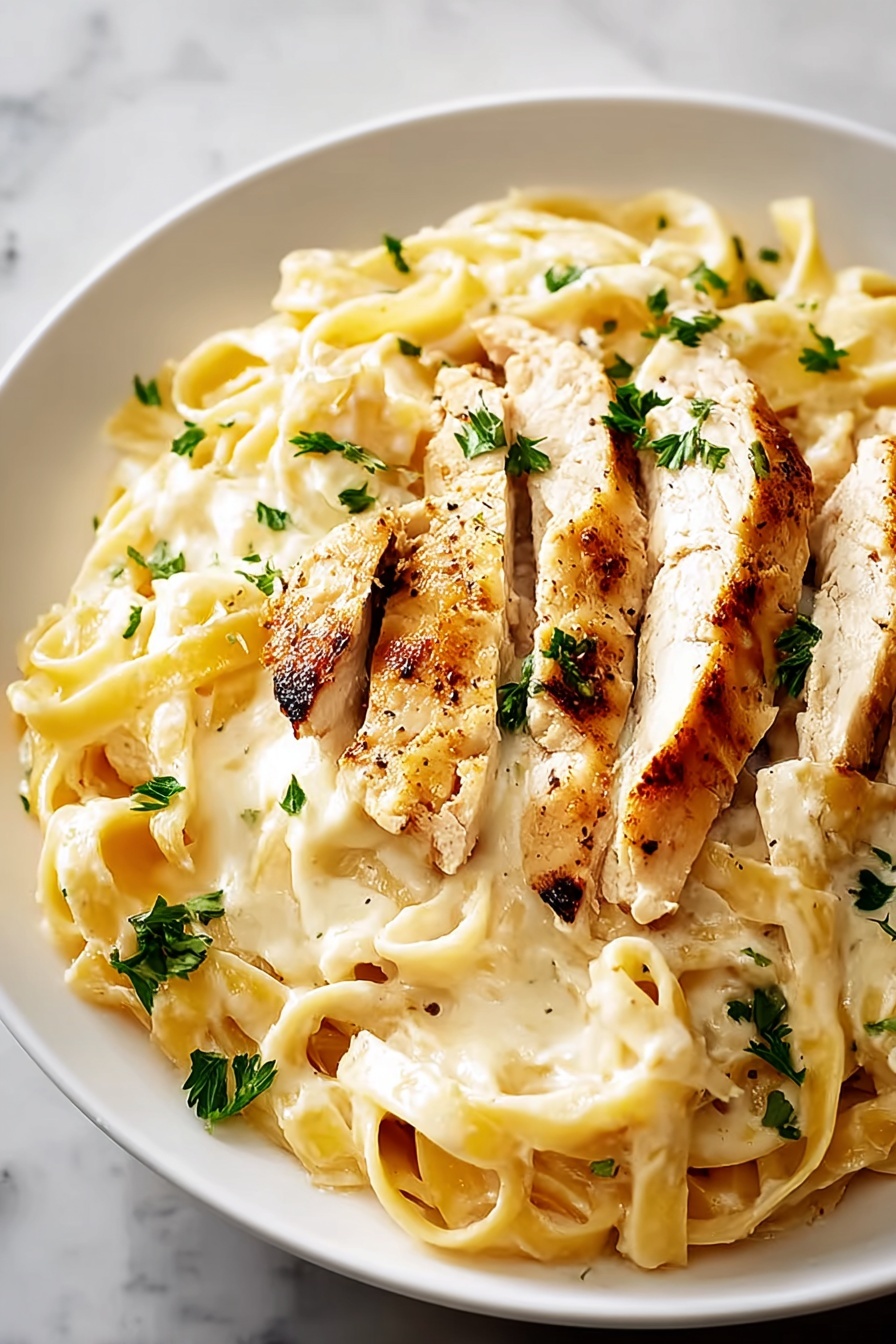 A plate of pasta with chicken on top.
