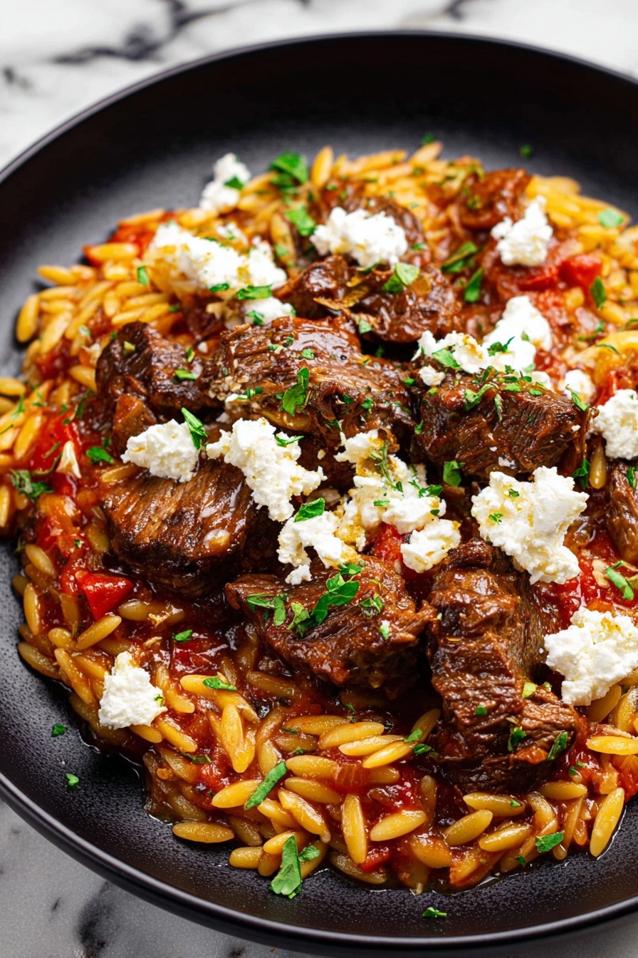 A plate of beef giouvetsi with feta cheese and tomatoes.
