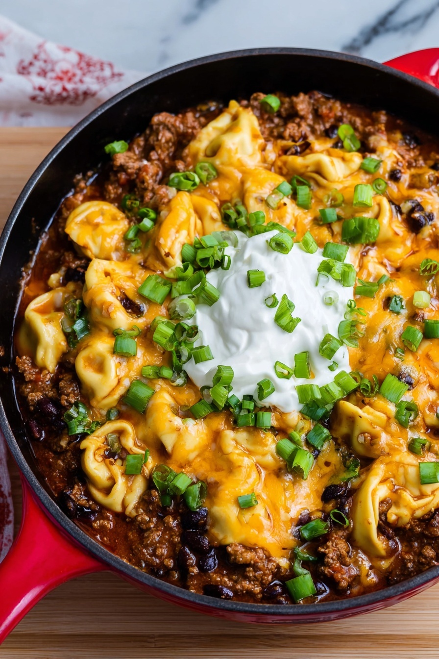 A skillet filled with a cheesy beef enchilada and tortellini.