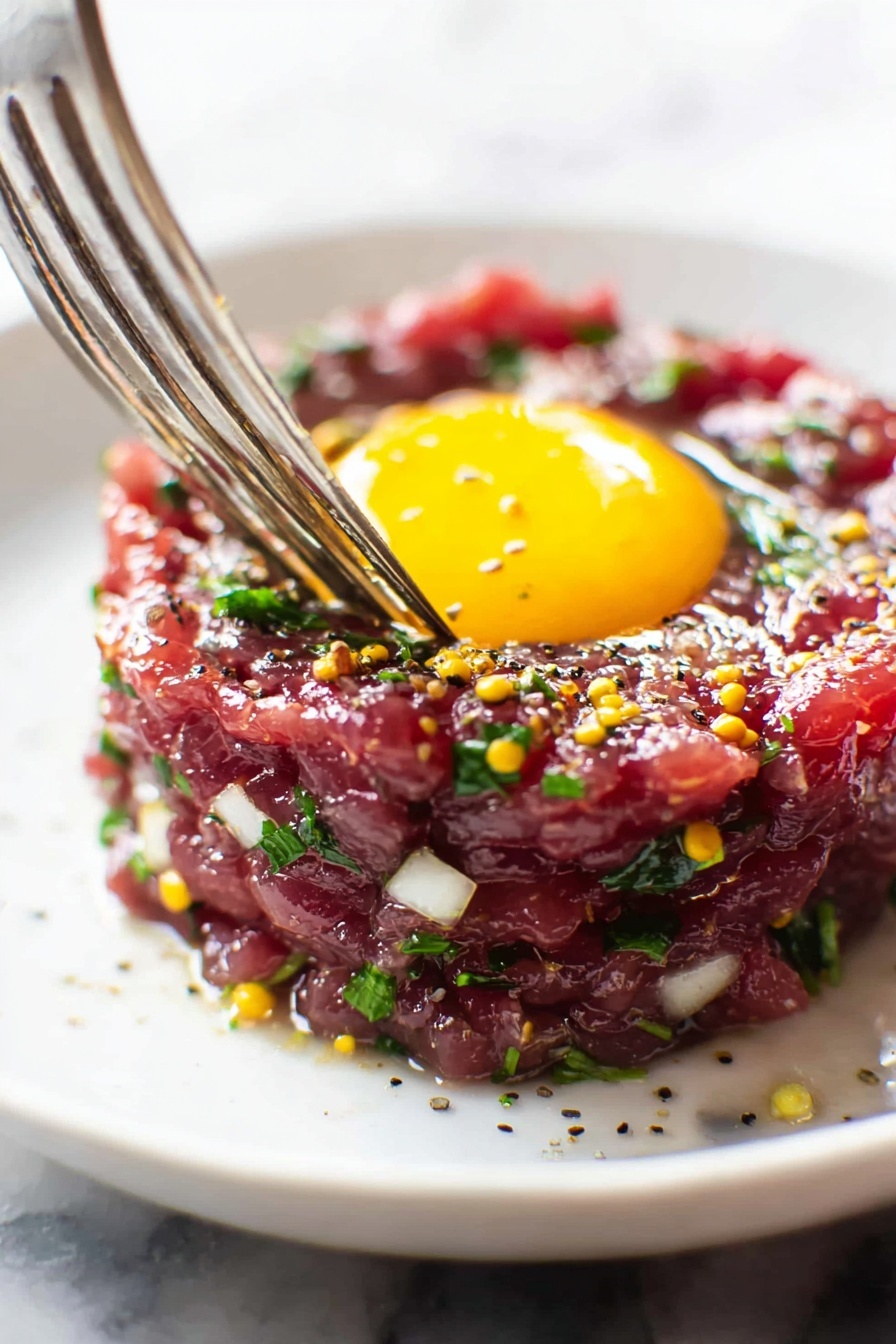 A close up of a bison tartare with a fried egg on top.