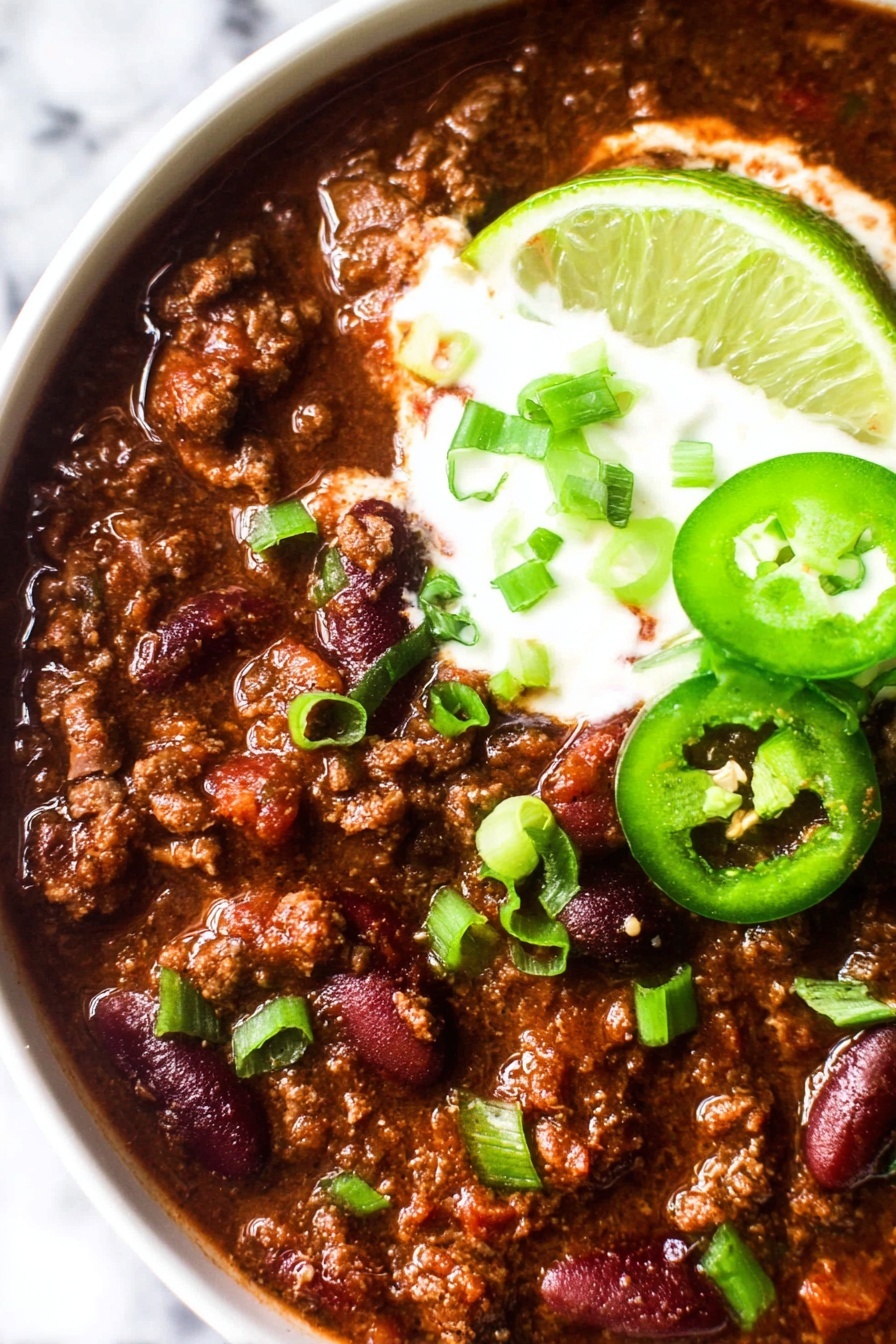 A bowl of chili with green onions on top.