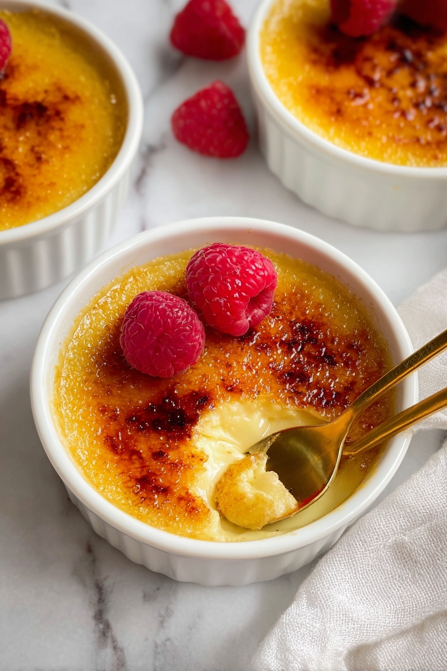 A bowl of vanilla creme brulee with raspberries on top.