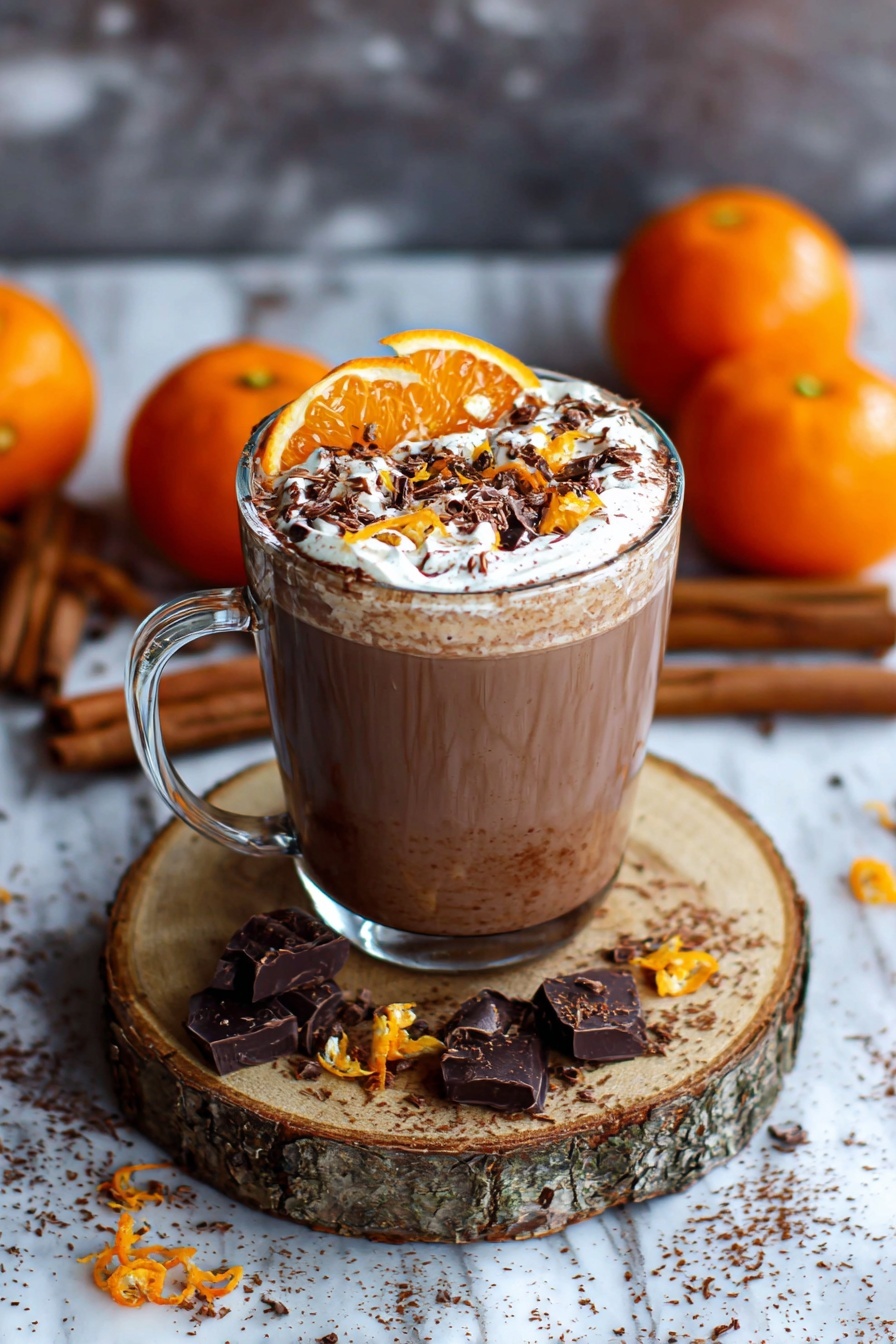 A glass of orange hot chocolate with whipped cream.