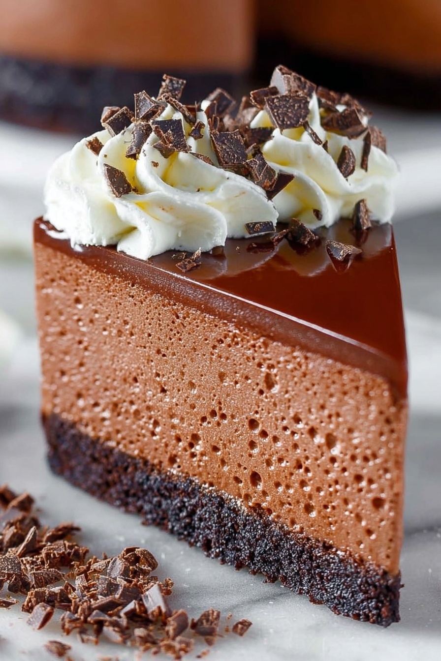 A slice of chocolate cheesecake with white whipped cream on top.
