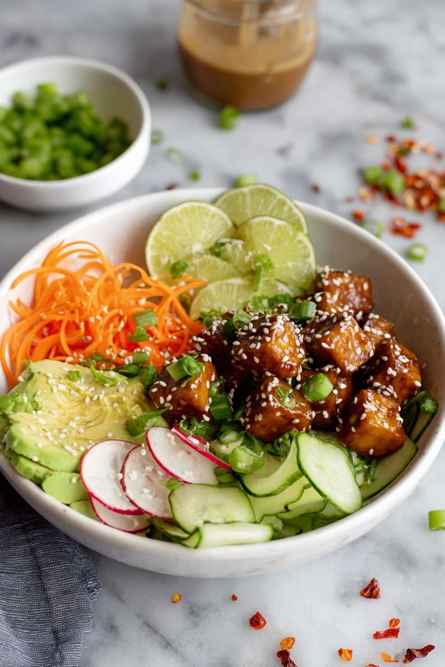 A bowl of food with a variety of ingredients including tofu, noodles, and vegetables.