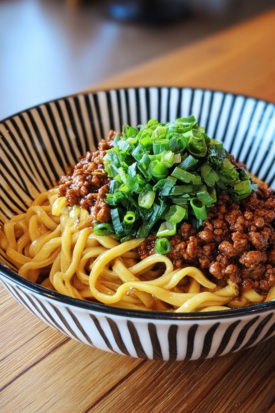 A bowl of noodles with meat and vegetables.