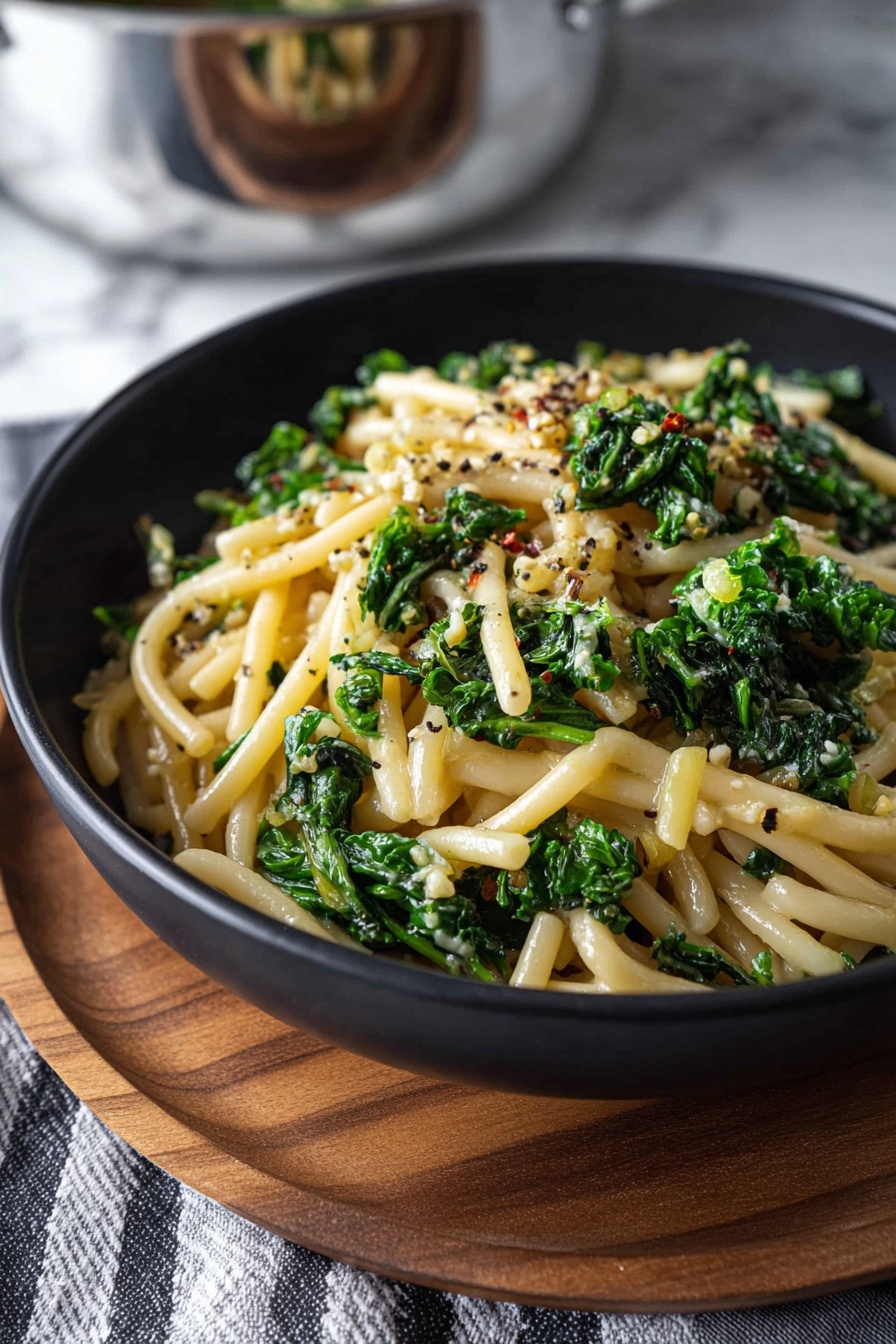A bowl of pasta with spinach and butter.