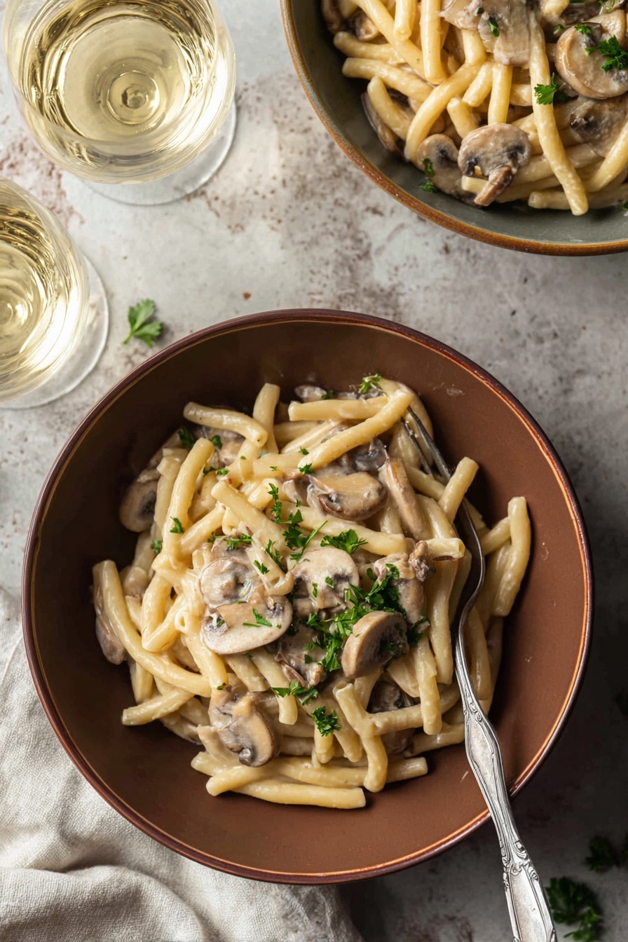 A bowl of pasta with mushrooms and herbs.