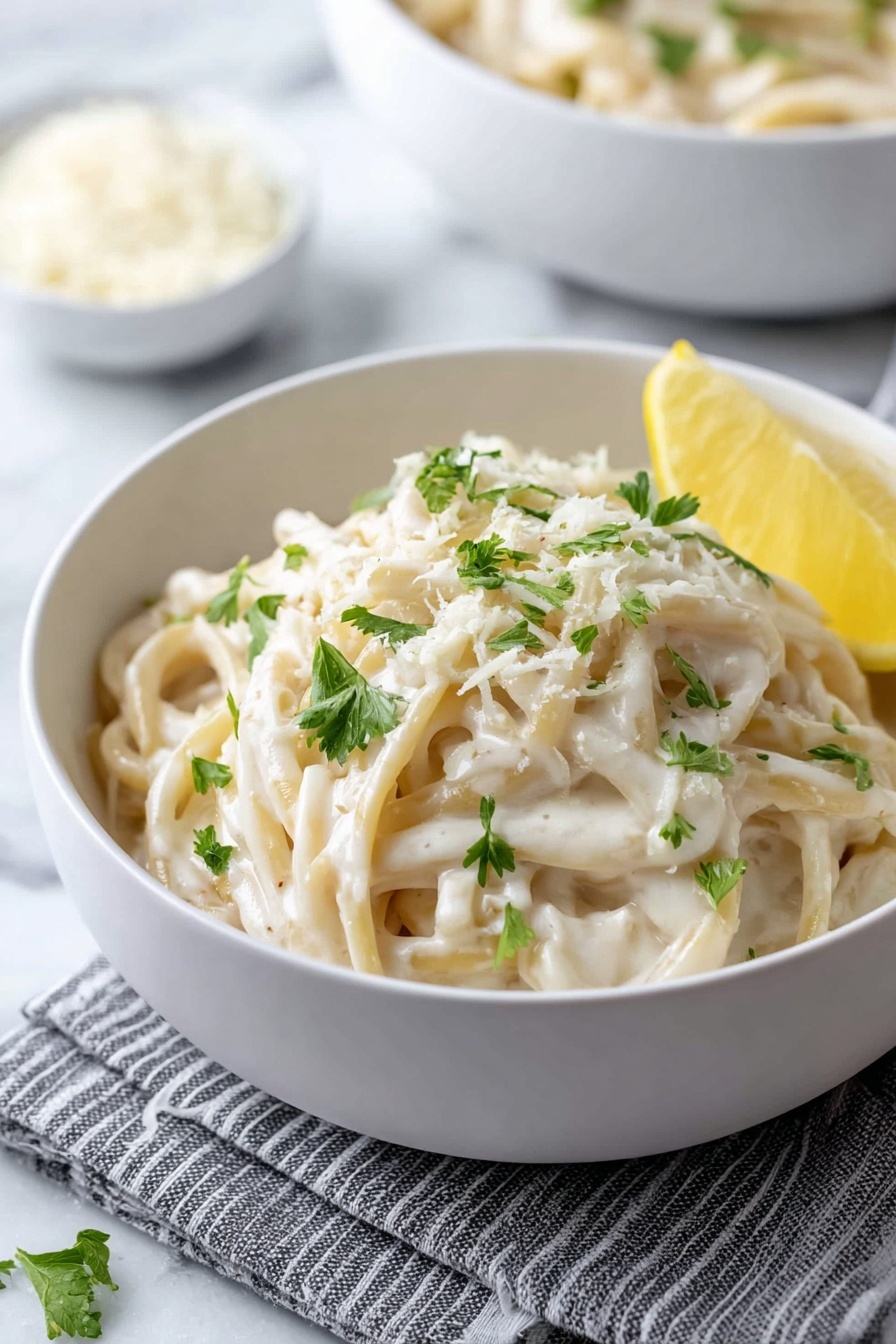 A bowl of pasta with cheese and lemon.