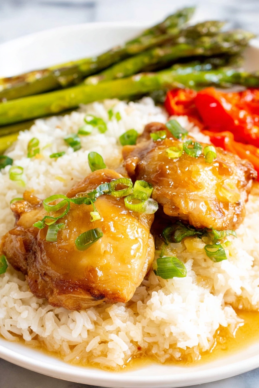 A plate of chicken adobo with rice and vegetables.