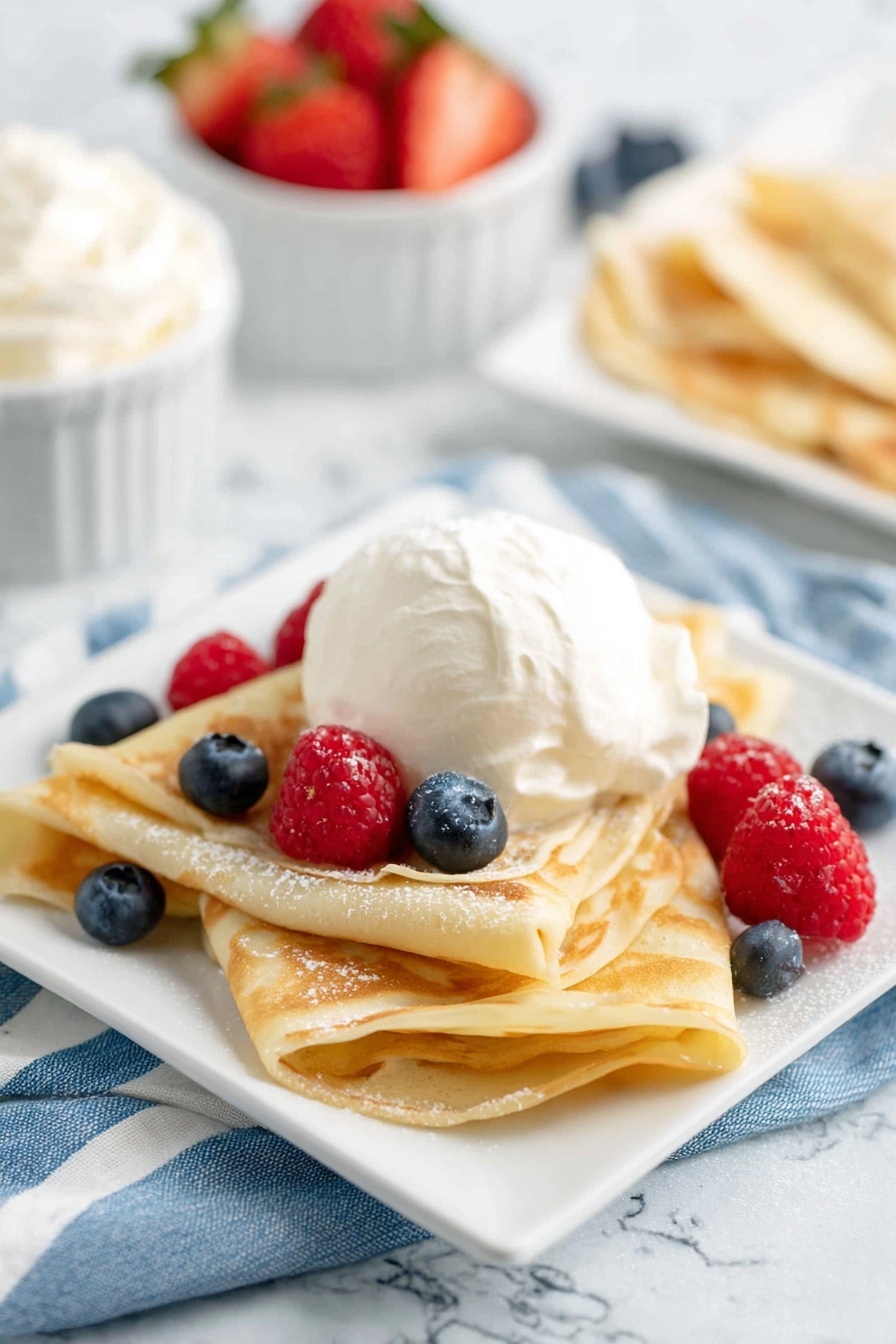 A plate of crepes with blueberries and whipped cream.