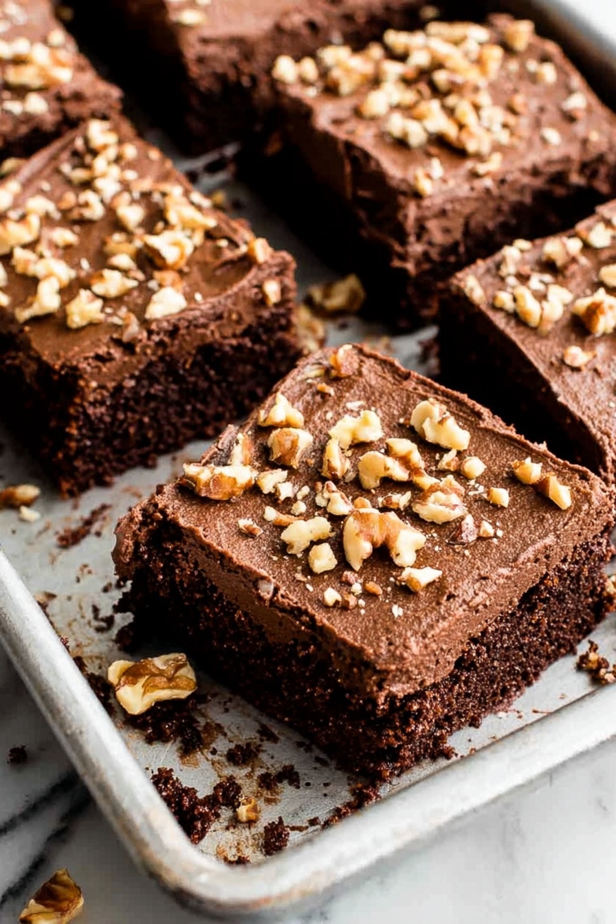 A piece of chocolate cake with nuts on top.