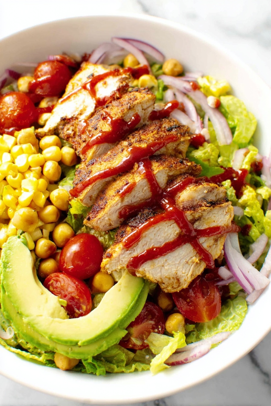 A plate of food with chicken, tomatoes, corn, and lettuce.