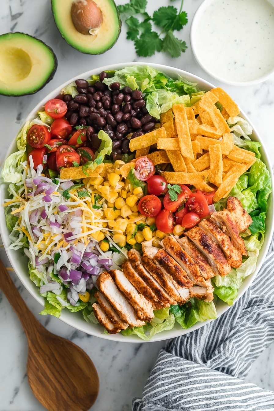 A bowl of BBQ chicken salad with lettuce, tomatoes, beans, and corn.