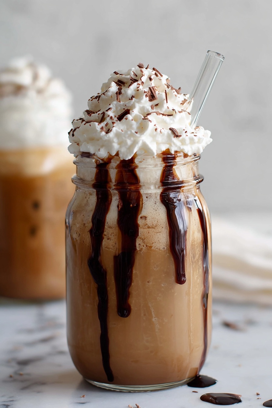 A glass of iced mocha coffee with whipped cream.