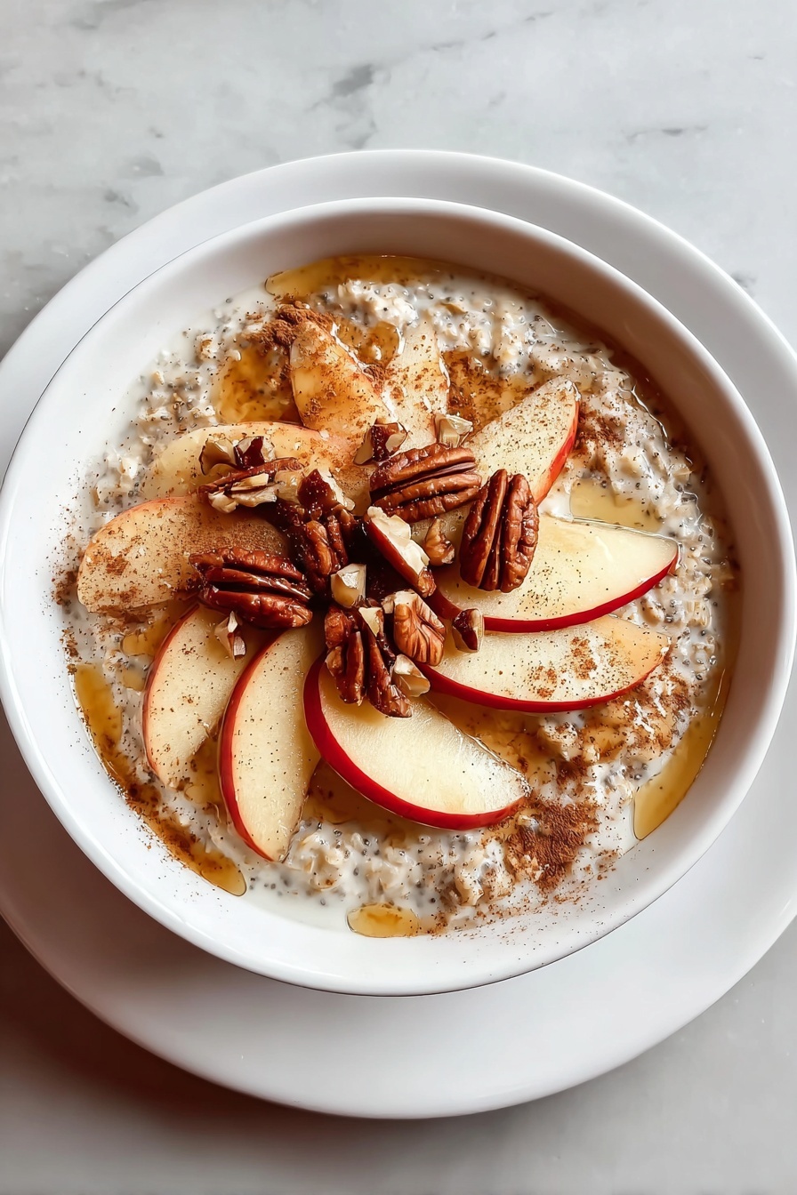 A bowl of oatmeal with nuts and apples.