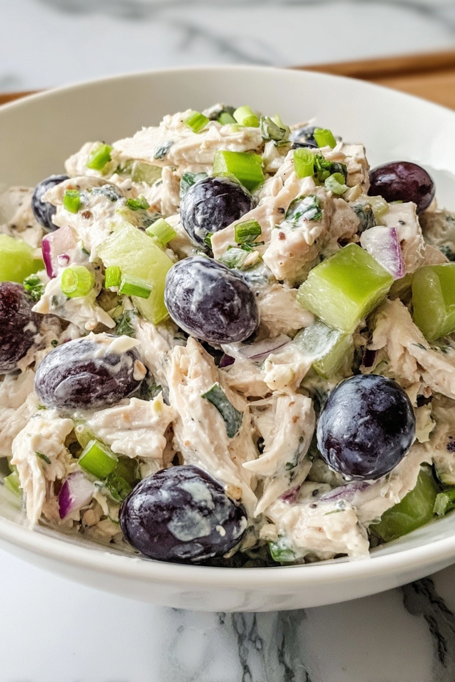 A bowl of chicken salad with grapes and walnuts.