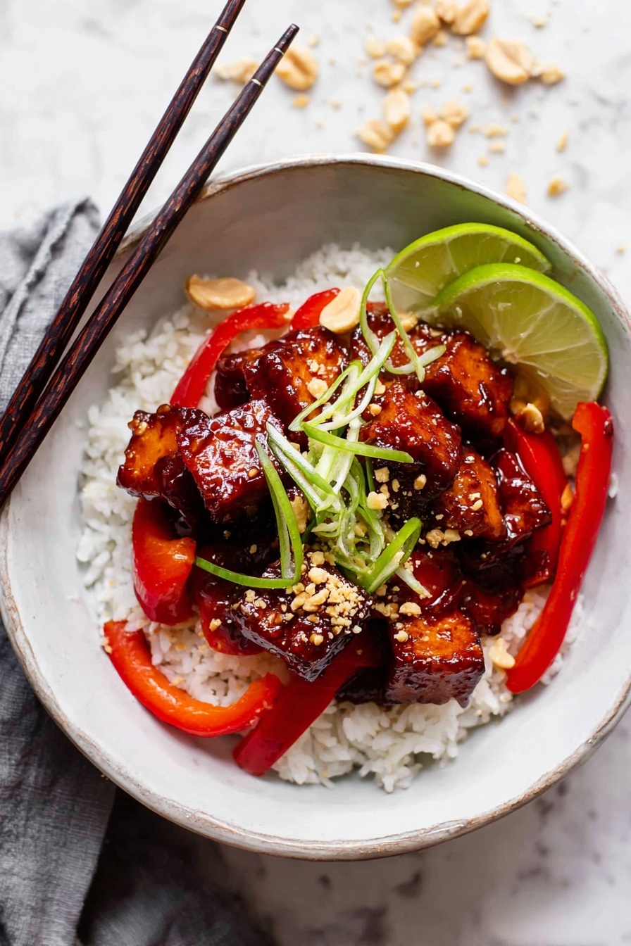 A bowl of sticky chicken with rice and peppers.