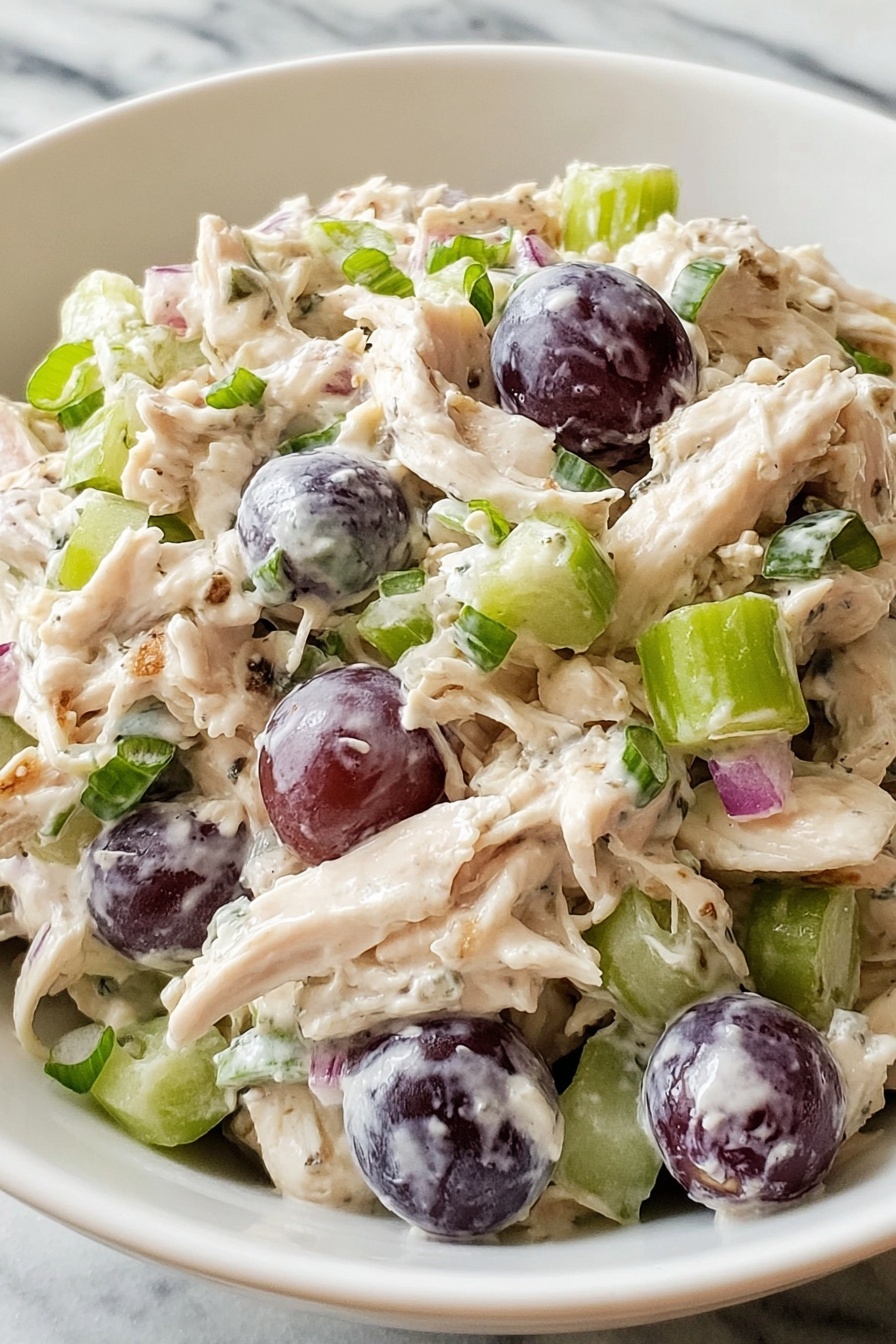A bowl of chicken salad with grapes and walnuts.