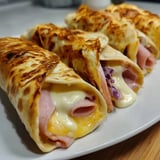 There’s a burrito and a sandwich on a plate, ready to eat.