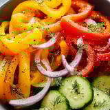 A big bowl filled with chopped cucumbers, peppers, and onions.