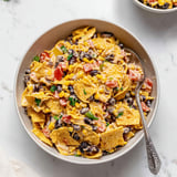 A bowl of nachos with beans and tomatoes.