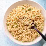 A bowl of noodles with green onions.