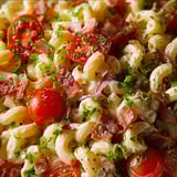 A dish of pasta with tomatoes and bacon.