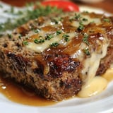 Plate with cheese-covered meatloaf and onions