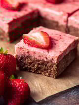 A slice of brownies with a strawberry on top.