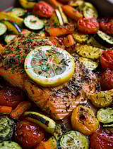 A piece of salmon with lemon and herbs on top.