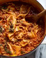 A bowl of lasagna soup with a spoon in it.