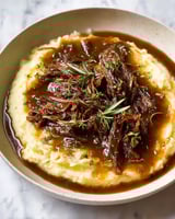 A bowl of pot roast with gravy.