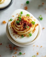 A white bowl with a green onion on top.