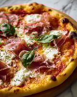 A pizza with white sauce and ham.