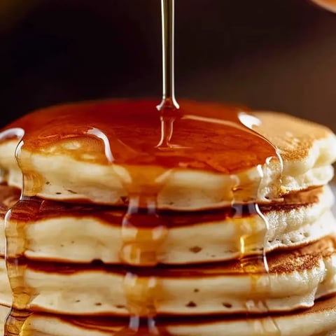 Syrup pouring onto a pancake stack.