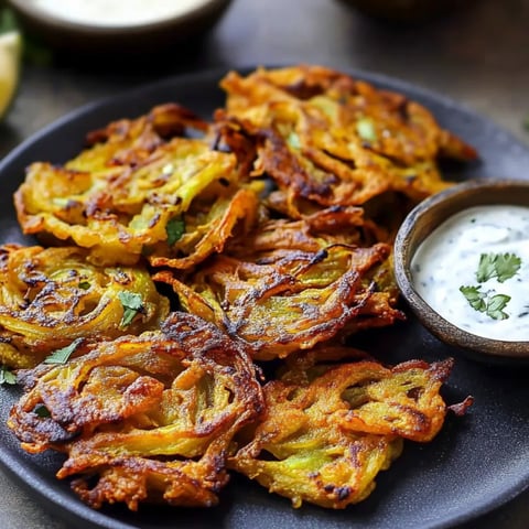 Hot crispy onion patties beside a cup of tasty dip.