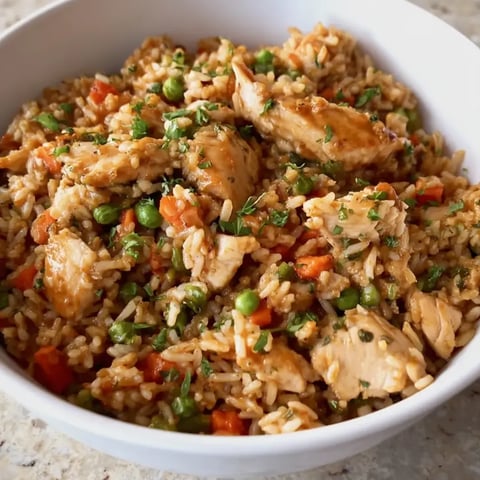 A serving bowl filled with rice, chicken, and peas.
